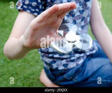 Ein Kind spielt mit einem drehenden Fidget Spinner im Garten Stockfoto