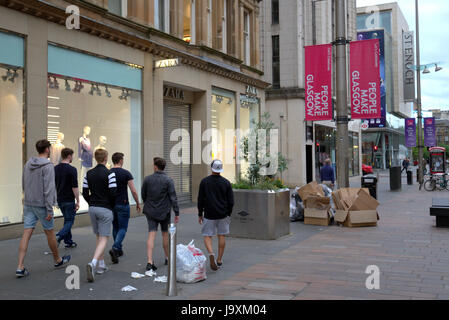 große Gruppe junger Teenager Männer wandern zwischen Müll und Abfall Einkaufen auf der Straße von Glasgow Stockfoto