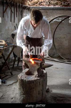 Traditionellen Hufschmied machen Hufeisen mit Hammer und Amboss und Roheisen Metall, Wales, UK Stockfoto
