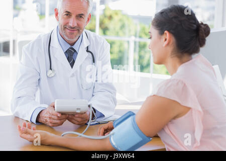 Lächelnd Arzt den Herzschlag eines Patienten im Büro der Einnahme Stockfoto