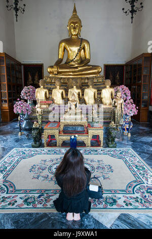 Ein junger Pilger betet in einem Schrein im Wat Pho, Bangkok, Thailand Stockfoto