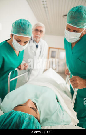 Patienten, die auf einem medizinischen Bett neben Ärzten im Krankenhausflur liegend Stockfoto