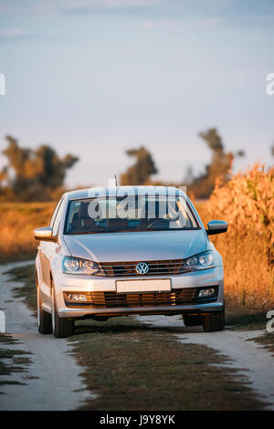 Gomel, Weißrussland - 14. September 2016: Volkswagen Polo Vento Limousine Parkplatz in der Nähe von Landstraße im Herbst Feld im sonnigen Abend. Stockfoto