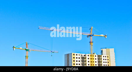 Große Krane über das unfertige Wohnung Haus Gebäude. Stockfoto