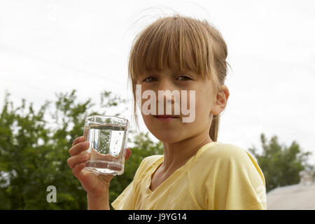 das Kind hält ein Glas Wasser in seinen Händen. selektiven Fokus. Stockfoto