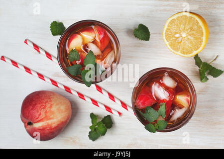 Pfirsich Eistee in Glas auf weißem Hintergrund aus Holz. Ansicht von oben Stockfoto