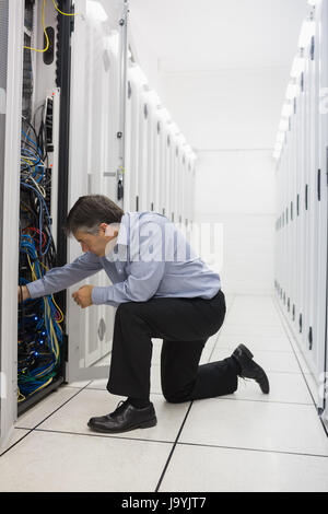 Mann kniete und Befestigung von Leitungen im Data center Stockfoto