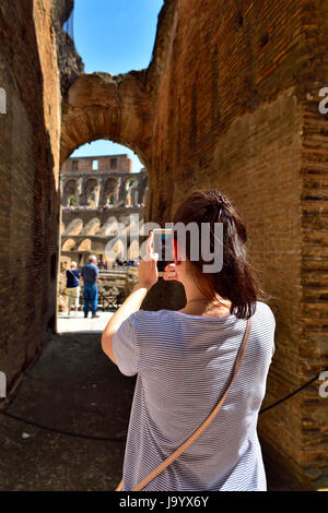 Frau, die ein Foto mit Handy-Kamera auf der Suche durch Bogen in das Kolosseum, Rom, Italien Stockfoto