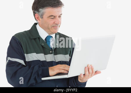 Reife Mechaniker in Overalls mit Laptop auf weißem Hintergrund Stockfoto