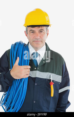 Porträt von zuversichtlich männlichen Mechaniker mit gerollten Draht und Bauarbeiterhelm auf weißen Hintergrund Stockfoto
