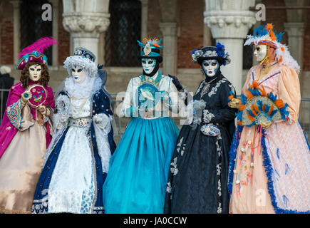 Fünf bunt gekleidete maskierte Frauen zur Feier von Carnevale vor dem Dogenpalast in Venedig, Italien Stockfoto