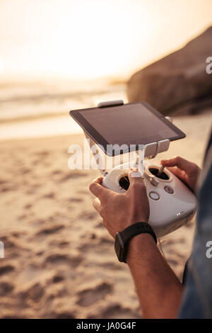 Schuss des jungen Mannhände halten Fernbedienung einer fliegenden Drohne am Strand beschnitten. Mann mit einem Rc-Controller für eine Drohne. Stockfoto