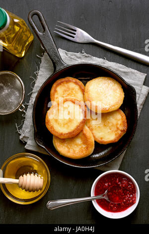 Käsekuchen, Quark-Pfannkuchen in Pfanne auf dunklem Hintergrund, Ansicht von oben Stockfoto