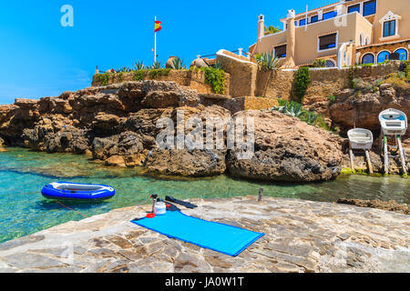 Flossen schwimmen und Sonnenbaden Matte auflegen Rock Plattform und Schlauchboot Boot auf dem Wasser in der Bucht Cala Xarraca, Insel Ibiza, Spanien Stockfoto