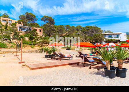 Insel IBIZA, Spanien - 17. Mai 2017: Menschen entspannen auf Holz-Terrasse mit Liegestühlen und Sonnenschirmen am Strand in Cala Carbo Bucht, Insel Ibiza, Spanien. Stockfoto