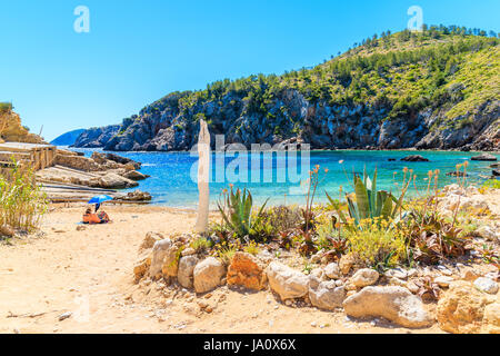 Paar von nicht identifizierten Personen Sonnenbaden an einsamen Cala d ' en Serra Strand, Insel Ibiza, Spanien Stockfoto