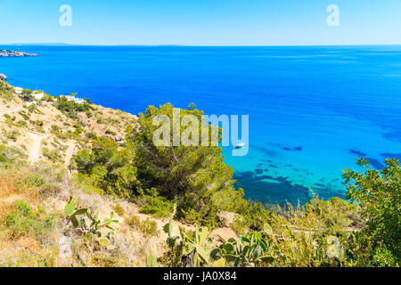 Segelboot am blauen Meer und hohen Felsen in der Nähe von Es Cubells Dorf im südlichen Teil der Insel Ibiza, Spanien Stockfoto