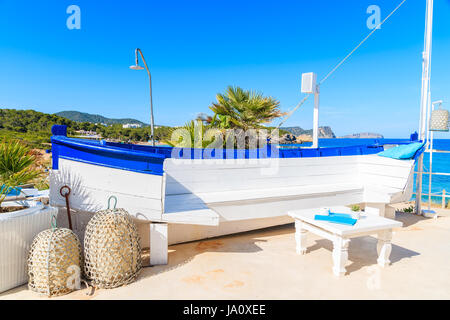 Weißer Schädel eines Fischerbootes auf sonnigen Terrasse am Strand von Cala Nova, Insel Ibiza, Spanien. Stockfoto