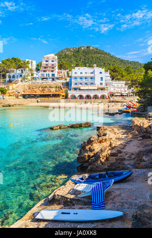 Kajak und Schlauchboot Boot am Meer und Blick auf die Hotels in Cala Portinatx bay, Insel Ibiza, Spanien Stockfoto