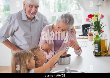 Lächelnde Großeltern Hilfe für Kinder in der Küche kochen Stockfoto