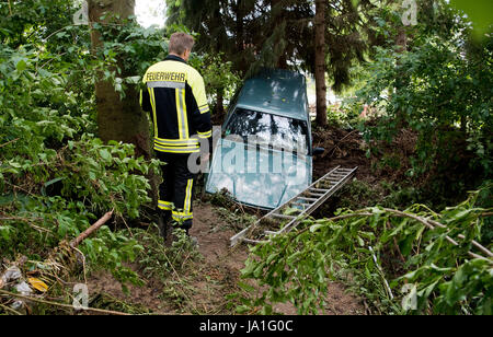 Holle, Deutschland. 4. Juni 2017. Ein Feuerwehrmann steht vor einem Auto, das durch einen Strom von Wasser im Sottrumer in der Nähe von Holle, Deutschland, 4. Juni 2017 mitgeführt wurde. Ein schweres Gewitter mit starkem Regen verursacht schwere Schäden in Teilen der Region Hildesheim Samstag nachts. Ein kleiner Bach in Sottrumer verwandelte sich in einen Strom von Wasser, trägt entfernt mehrere Autos. Foto: Julian Stratenschulte/Dpa/Alamy Live News Stockfoto