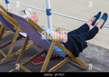 Weymouth, Dorset, UK. 4. Juni 2017. UK-Wetter: Kühler und trüber mit sonnigen Abschnitten am Weymouth - Besucher gehen zum Meer am Strand von Weymouth. Frau entspannen im Liegestuhl auf Esplanade Credit: Carolyn Jenkins/Alamy Live News Stockfoto