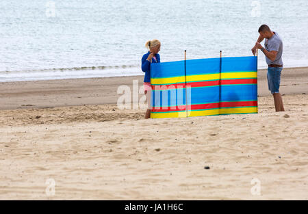 Weymouth, Dorset, UK. 4. Juni 2017. UK-Wetter: Kühler und trüber mit sonnigen Abschnitten am Weymouth - Besucher gehen zum Meer am Strand von Weymouth. Paar, das Aufstellen von Windschutz Credit: Carolyn Jenkins/Alamy Live News Stockfoto