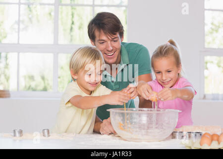 Kinder brechen Eiern in einer Schüssel in Küche Stockfoto