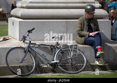 Radfahrer im Sitzen lesen Karte mit Fahrrad gegen Denkmal in George Square Glasgow Stockfoto