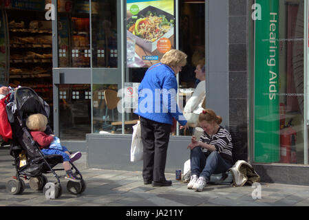 Obdachlose im Vereinigten Königreich auf der alten Straße bettelnde Dame helfen Kind zeugen Stockfoto