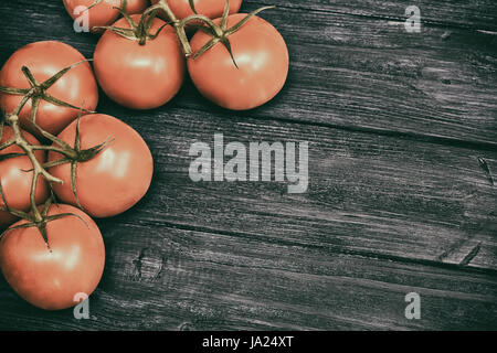 Rote Cherry-Tomaten auf dunklen hölzernen Hintergrund. Ansicht von oben. Vintage getönt Stockfoto