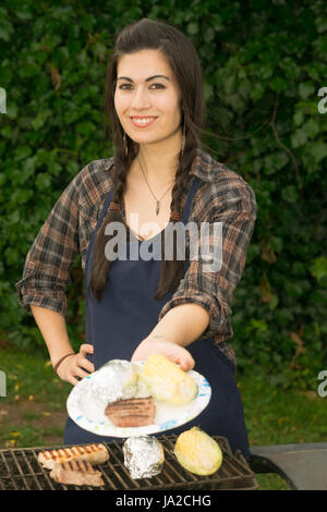 Entzückende Frau Hände Essen über dem Grill im Garten Stockfoto