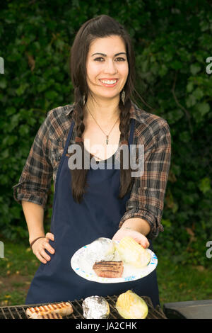 Entzückende Frau Hände Essen über dem Grill im Garten Stockfoto