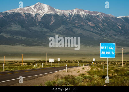 Ein Schild warnt, dass die nächste Tankstelle 80 Meilen entfernt, mit einem schneebedeckten Berg im Hintergrund. White Pine County in Nevada. Stockfoto