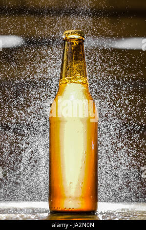 Eine einzige Flasche Bier mit Wasserblasen in der Luft auf unscharfen Hintergrund Nahaufnahme Stockfoto