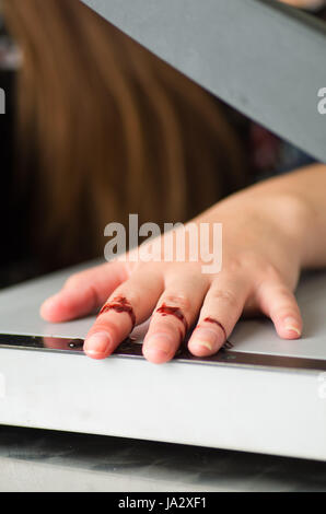 Schließen sich einer Frau mit einem Papierschneider hatte einen Unfall und schneiden Sie ihre Finger Stockfoto