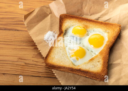 frittierte Wachteleier in einem Toast auf hölzernen Hintergrund Stockfoto