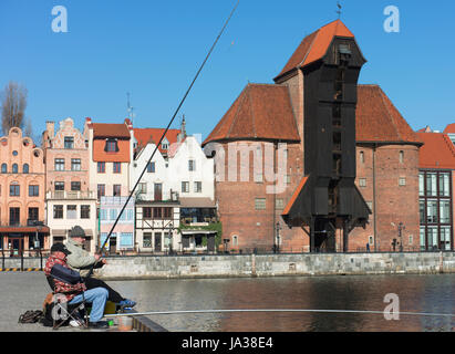 Männer angeln auf der Mottlau in der Danziger Altstadt mit der mittelalterlichen Kran und National Maritime Museum im Hintergrund. Stockfoto