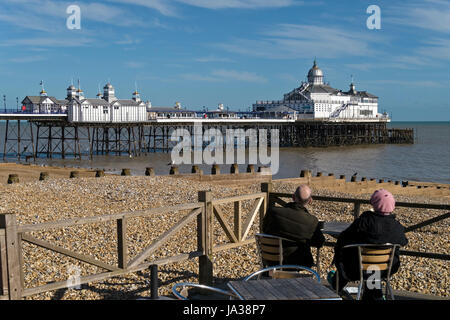 Sitzenden paar Aussicht auf Eastbourne Pier mit Kiesstrand im Vordergrund, East Sussex, England, UK Stockfoto