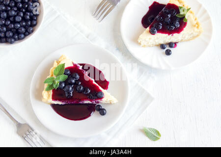 Hausgemachter Käsekuchen mit frischen Bio-Heidelbeeren, Beerensauce und Minze zum Nachtisch Stockfoto