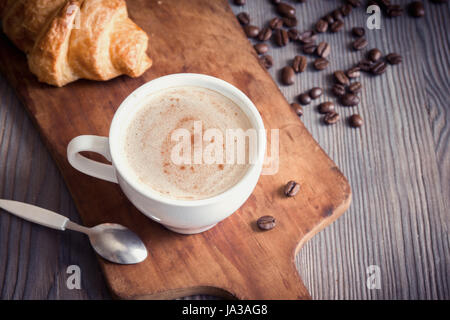 Kaffee mit Croissant zum Frühstück. Cappuccino Kaffee, Tönung Bild mit Textfreiraum. Stockfoto