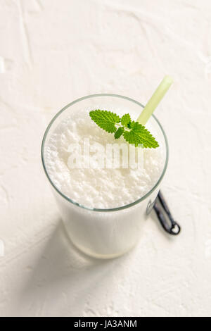 Vanille-Shake mit Minze auf weißem Hintergrund. Vanille-Eis-Milch-Shake. Bananen-Smoothie mit Minze und Vanille. Stockfoto