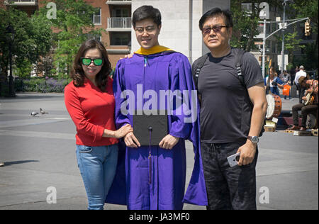 Eine chinesische Gaststudent feiert seinen Abschluss an der NYU mit seinen Eltern. Im Washington Square Park in New York City Stockfoto