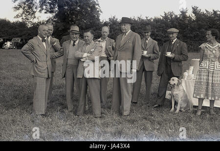 1950er-Jahren, historische. Gruppe von gut gekleideten Herren stehen zusammen mit einer Tasse Tee auf einer Fete oder Outdoor-Event. Stockfoto