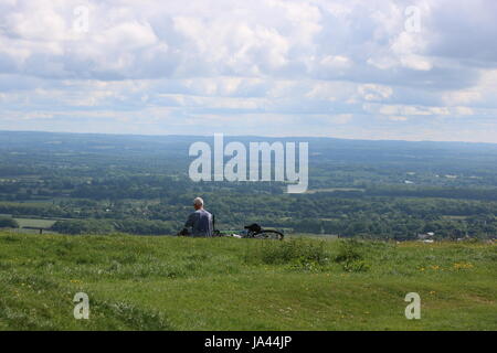 Ein Radfahrer nimmt eine Pause auf der South Downs Way in der Nähe von Brighton, Blick auf die beeindruckende Landschaft an einem sonnigen Tag. Stockfoto