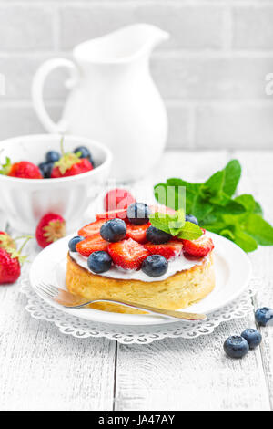 Leckere Beeren-Käsekuchen mit frischen Erdbeeren und Heidelbeeren auf weißem Hintergrund Stockfoto