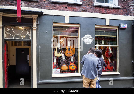 Tin Pan Alley Guitar Shop - Passanten sehen die Vintage-Gitarren zum Verkauf im No.Tom Store in der historischen Denmark Street im Zentrum von London Stockfoto