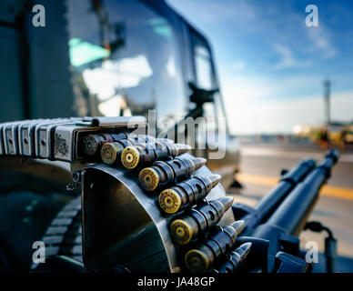 Großkalibrige Kugeln im Gürtel aus nächster Nähe. Defokussierten Hintergrund des Hubschraubers und der zugehörigen Waffe. Bilder für Waffen, Militär und Krieg. Stockfoto