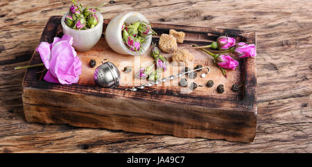 Trocknen Sie Rosenknospen Tee. Teesieb und Rosenknospen auf einem hölzernen Hintergrund Stockfoto