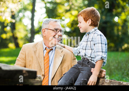 Großvater und Enkel sitzen und reden im park Stockfoto